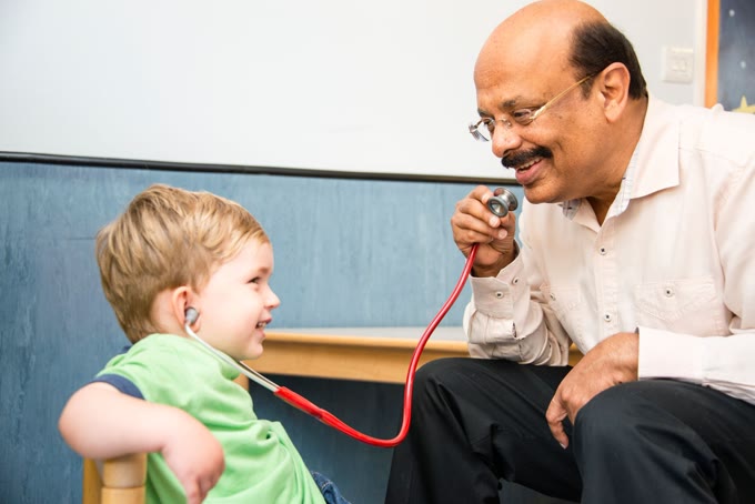 Dr Rajiv Sood lets a young boy listen with a stethoscope during a paediatric consultation
