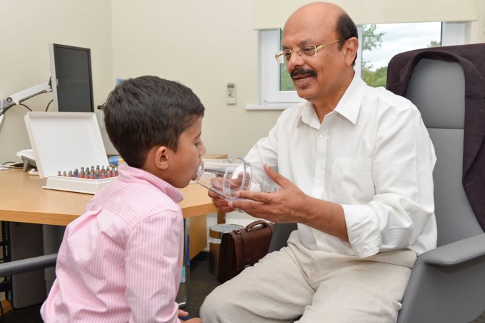 Dr Rajiv Sood demonstrating an inhaler spacer device to a child during allergy treatment